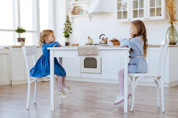 two children sitting on the kitchen table. - Foto, Bild