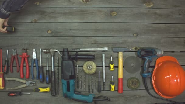 A variety of electro and hand tools. Slow motion. Top view.Male hand stretches a measuring tape on the table.On the table are tools for various types of construction and repair work on wood, metal, concrete, plastic and other materials. - Footage, Video