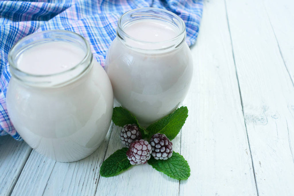 Brombeerjoghurt in Gläsern auf weißem Holzgrund. - Foto, Bild