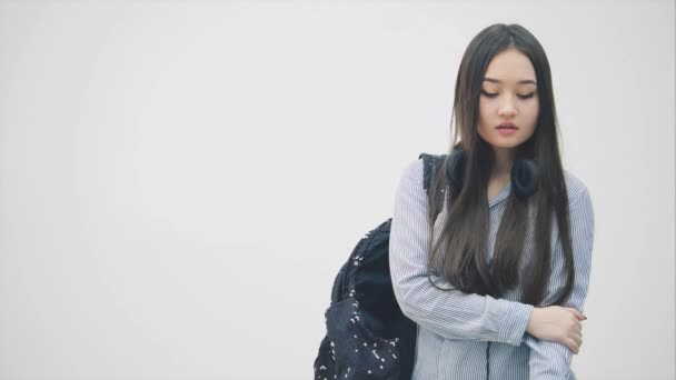 Young asian girl with backpack over her shoulder calling someone, but cant reach him, hiding phone, looking angry and disappointed. - Záběry, video