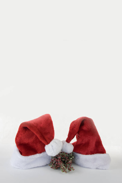 Vertical Santa and mrs Claus red hat kissing on white background copy space - Photo, Image