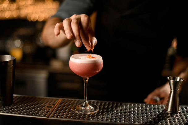 Close up of bartender decorating alcohol cocktail - Foto, afbeelding