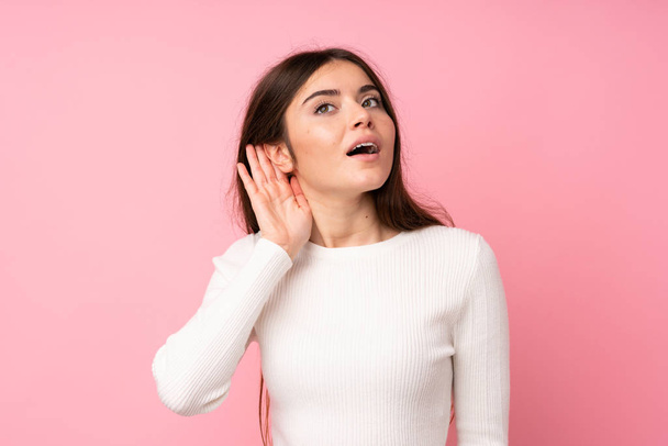 Young woman over isolated pink background listening something - Foto, immagini