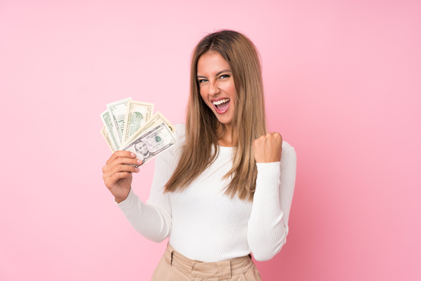 Giovane donna bionda su sfondo rosa isolato prendendo un sacco di soldi
 - Foto, immagini