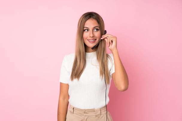 Young blonde woman over isolated pink background working with headset - Fotoğraf, Görsel