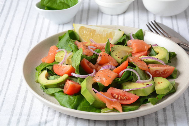 Mediterranean Avocado Salmon Salad with spinach, cherry tomatoes, avocado and red onion dressing. Concept for a tasty and healthy meal. Vegan food - Photo, Image