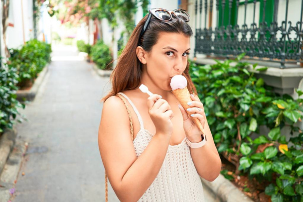 Young beautiful woman eating ice cream cone on a sunny day of summer on holidays - Φωτογραφία, εικόνα