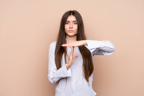 Young woman over isolated background making time out gesture - Photo, image