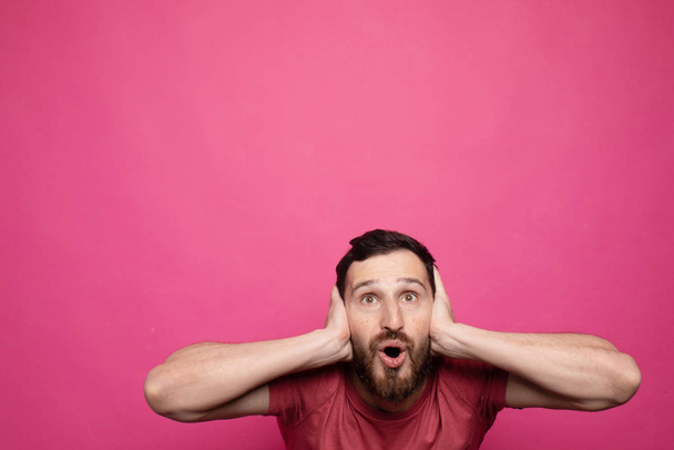 Happy glad young bearded man shoked with great news on pink background. - Foto, imagen