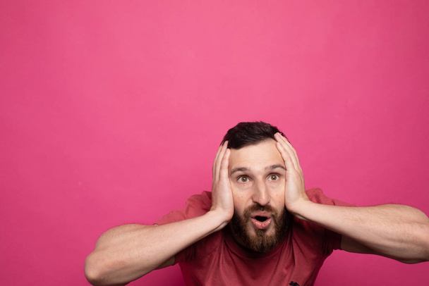 Happy glad young bearded man shoked with great news on pink background. - Foto, immagini
