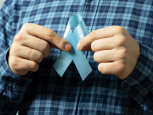 Ekose gömlekli bir adamın elinde prostat kanseri farkındalığının mavi kurdele sembolü var. Tıp ve erkek sağlığı anlayışı. - Fotoğraf, Görsel
