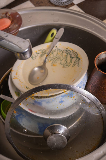 A mountain of unwashed utensils in a kitchen sink. Desolation an - Photo, Image