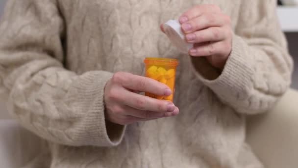 Η γυναίκα παίρνει βιταμίνες. Μια γυναίκα ανοίγει ένα βάζο με φάρμακα, χύνει ένα χάπι στην παλάμη της - Πλάνα, βίντεο