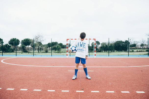 Jugador de fútbol niño sosteniendo la pelota a mano
 - Foto, Imagen