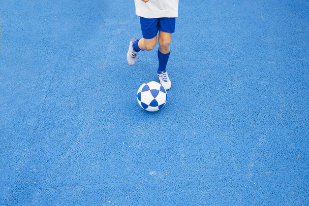 Piccolo ragazzo irriconoscibile che gioca a calcio di sfondo blu
 - Foto, immagini