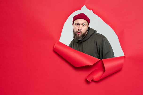 brutal funny man with a beard behind a red torn background - Foto, Bild