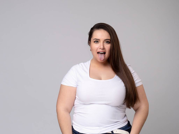 Plus Size Model with long hair Grimacing, pulling her cheeks. - Фото, изображение