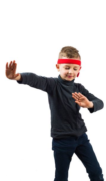 Pequeño jugador de karate. chico en el golf oscuro. y diademas rojas. sobre un fondo blanco
 - Foto, Imagen