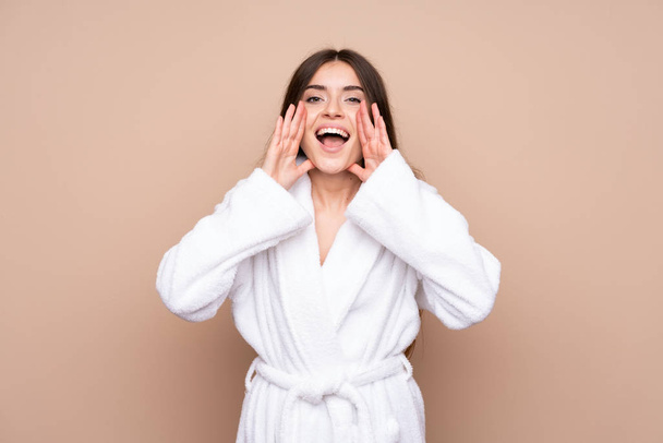 Young girl in a bathrobe over isolated background shouting with mouth wide open - Photo, image