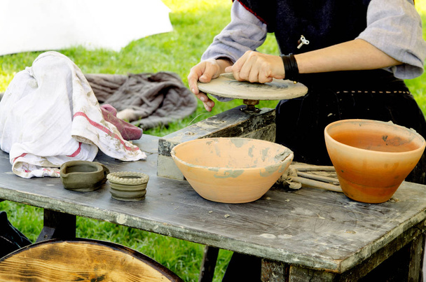 Donna che lavora con argilla fresca bagnata su ruote ceramiche. Mani femminili fanno piatto di ceramica in vecchio modo all'aperto
 - Foto, immagini