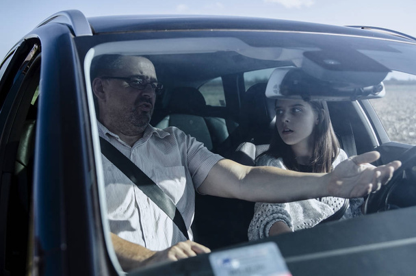 Teini-ikäinen tyttö ajokortin testissä, istuu kuljettajan istuimella miehen ohjaajan kanssa tentissä - Valokuva, kuva