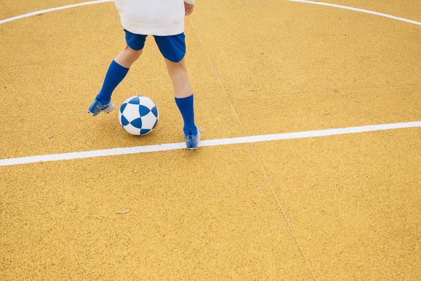 Menino irreconhecível jogando futebol de fundo amarelo
 - Foto, Imagem