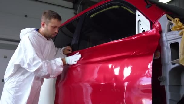 worker man is stroking dye on car body by hand in glove in auto service - 映像、動画