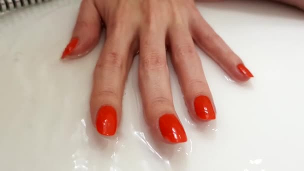 Rode nagels, klassieke manicure, vrouwelijke hand op een wit oppervlak met stromend water - Video