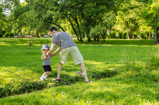 Baba ve küçük tatlı kız parkta oynaşıp sarılıyorlar. - Fotoğraf, Görsel