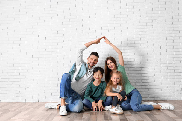 Happy family forming roof with their hands near brick wall. Insu - Foto, immagini
