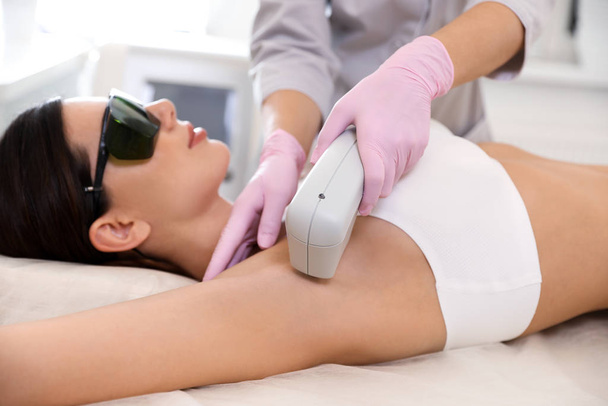 Young woman undergoing laser epilation procedure in beauty salon - Foto, immagini