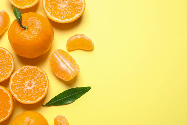 Flat lay composition with fresh ripe tangerines and leaves on light yellow background, space for text. Citrus fruit - Foto, afbeelding