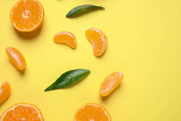 Flat lay composition with fresh ripe tangerines and leaves on light yellow background. Citrus fruit - Foto, afbeelding
