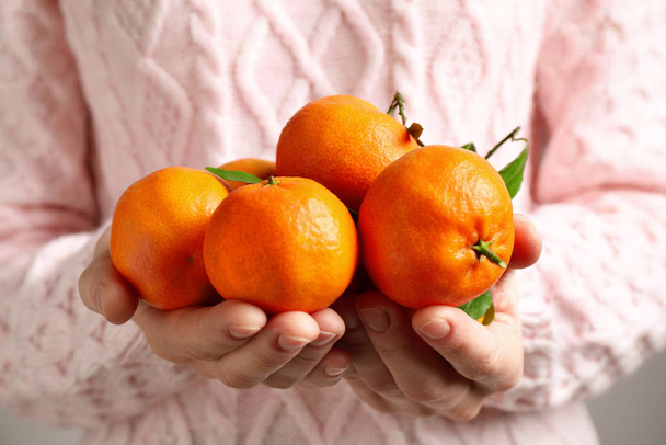 Woman holding pile of tangerines, closeup. Juicy citrus fruit - Фото, зображення