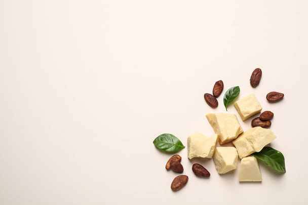 Organic cocoa butter and beans on beige background, flat lay. Space for text - Foto, Imagen