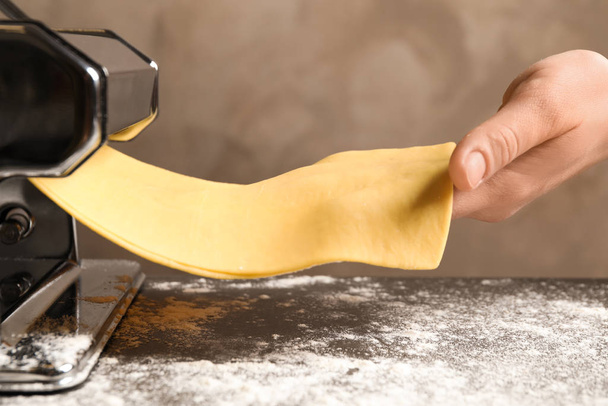 Woman preparing dough with pasta maker machine at table, closeup - Фото, изображение