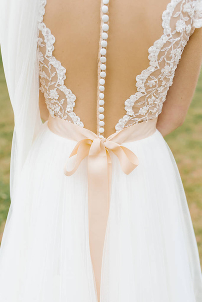 Hermoso vestido de dama de honor de boda sin respaldo con un montón de botones y arco beige
 - Foto, imagen