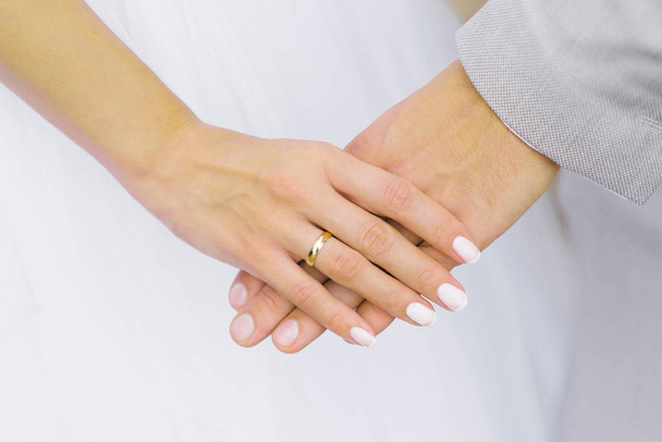 Η νύφη κρατάει το χέρι του γαμπρού. Δαχτυλίδι αρραβώνων στο δάχτυλό σου - Φωτογραφία, εικόνα
