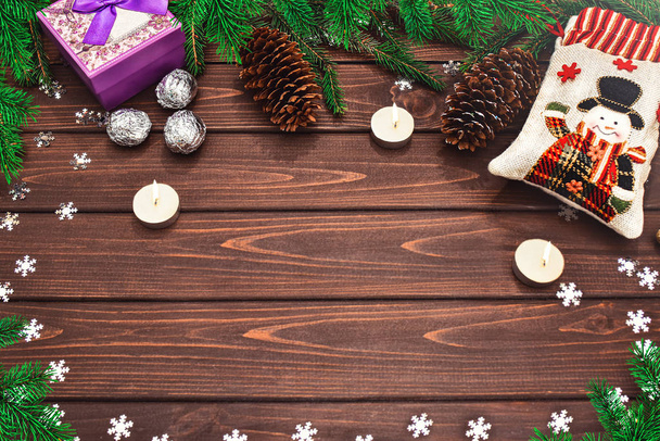 Fundo de Natal ramos de abeto, cones, Velas, doces e presentes em uma mesa de madeira. Espaço para SMS. Vista de cima. Ambiente de Natal
 - Foto, Imagem