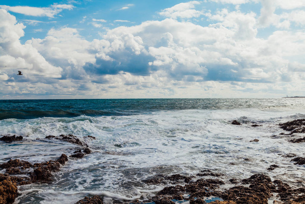 de stenen strand ocean wave hemel met wolken - Foto, afbeelding