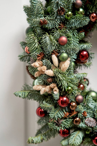 Close-up details van Prachtige kerstkrans van verse sparren op de witte deur. Toegang tot het huis. Kerststemming. Kerstboom. - Foto, afbeelding