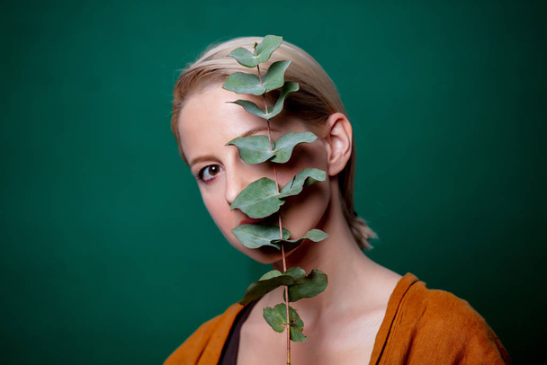 Woman holds eucalyptus branch on green background - Foto, afbeelding