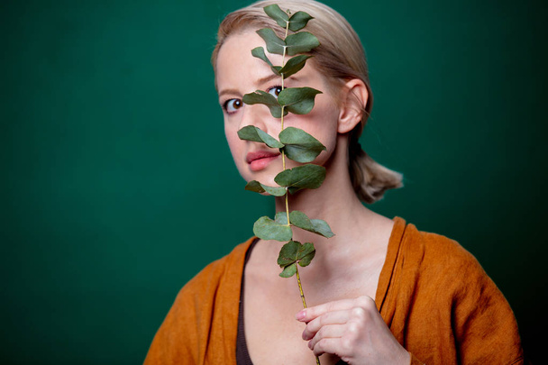 Woman holds eucalyptus branch on green background - Zdjęcie, obraz