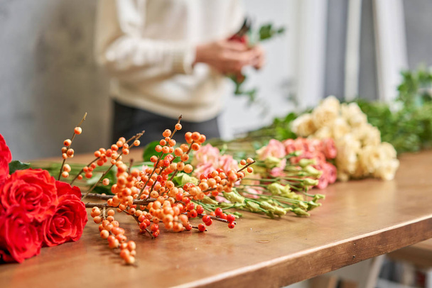 Βήμα-βήμα ανθοπώλης γυναίκα δημιουργεί κόκκινο όμορφο μπουκέτο από μικτή λουλούδια. Ωραία φρέσκια παρέα. Εκπαίδευση, master class και floristry μαθήματα. Παράδοση λουλουδιών. Ευρωπαϊκή ιδέα ανθοπωλείου. - Φωτογραφία, εικόνα