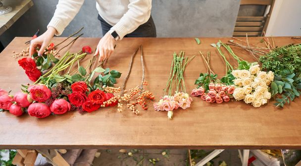 Step by step florist woman creates red beautiful bouquet of mixed flowers. Handsome fresh bunch. Education, master class and floristry courses. Flowers delivery. European floral shop concept. - Photo, Image