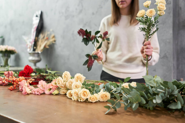 Step by step florist woman creates red beautiful bouquet of mixed flowers. Handsome fresh bunch. Education, master class and floristry courses. Flowers delivery. European floral shop concept. - Photo, Image