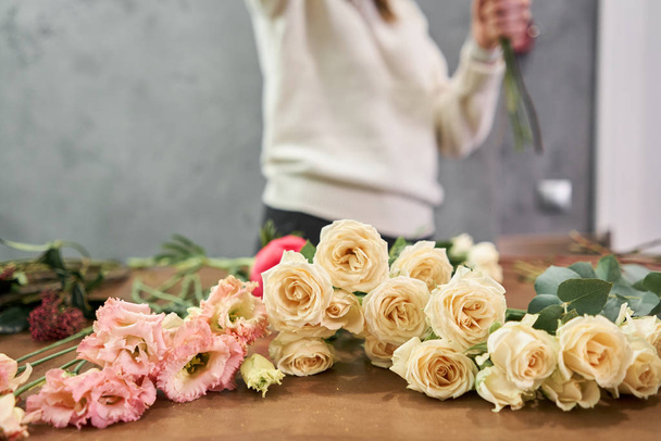 ステップバイステップの花屋の女性は混合花の赤い美しい花束を作成します。新鮮な束を教育、マスタークラスと花粉コース。花の配達だヨーロッパの花店のコンセプト. - 写真・画像