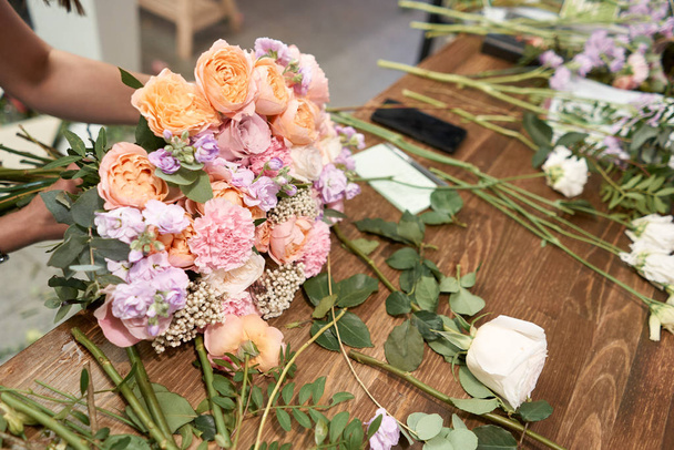 European floral shop concept. Florist woman creates beautiful bouquet of mixed flowers. Handsome fresh bunch. Education, master class and floristry courses. Flowers delivery. - 写真・画像