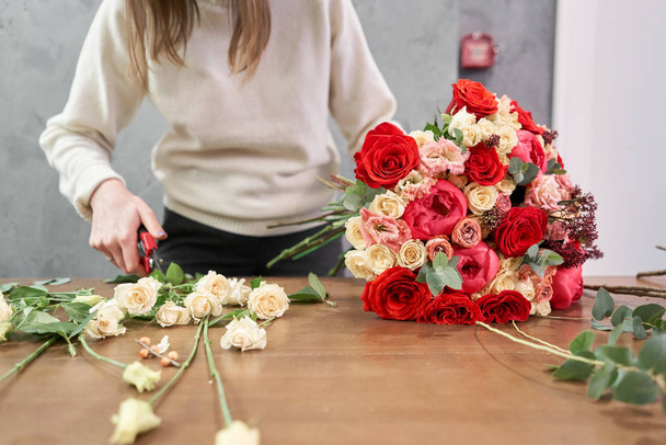 Lépésről lépésre virágárus nő teremt piros gyönyörű csokor vegyes virágok. Jóképű, friss bagázs. Oktatás, mesterkurzusok és virágtanfolyamok. Virágok szállítása. Az európai virágüzlet koncepciója. - Fotó, kép