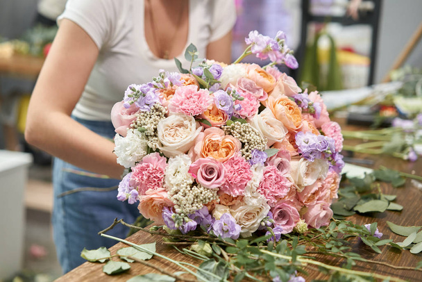 European floral shop concept. Florist woman creates beautiful bouquet of mixed flowers. Handsome fresh bunch. Education, master class and floristry courses. Flowers delivery. - Photo, Image